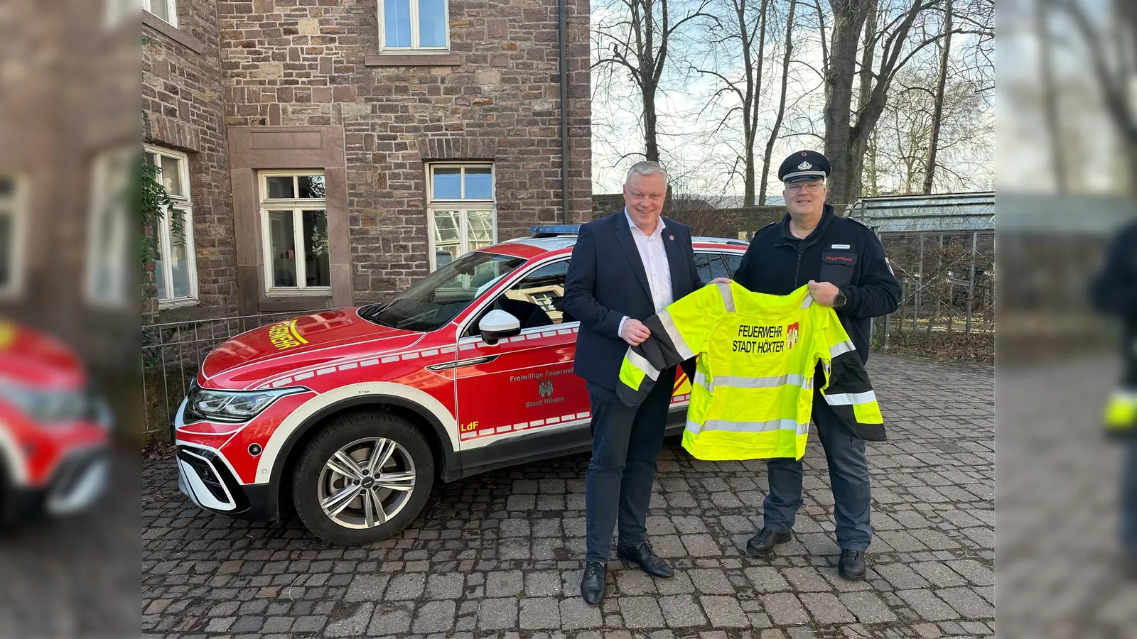 Wehrführer Jürgen Schmits überreicht Bürgermeister Daniel Hartmann symbolisch eine der neuen Wetterschutzjacken – ein wichtiger Schritt für die Sicherheit der Feuerwehrkräfte in Höxter. (Foto: Stadt Höxter)