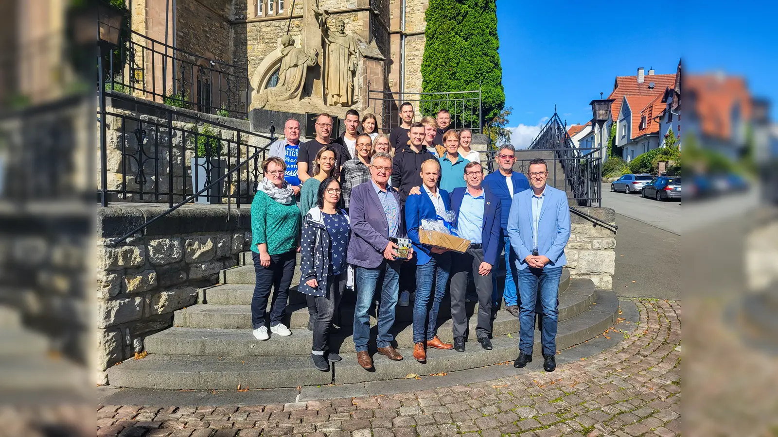 17 Vereinsmitglieder waren gemeinsam mit (vorne, v.l.) Bauamtsleiterin Gundula Manigk, Alt-Bürgermeister Herold Quick und dem ehrenamtlichen Bürgermeister Stephan Bawey angereist. Bürgermeister Tobias Scherf (2.v.r.) und der erste Beigeordnete Andreas Niggemeyer (r.) überreichten den Falkenberger Freunden bei bestem Wetter ein Präsent. (Foto: Stadt Warburg)