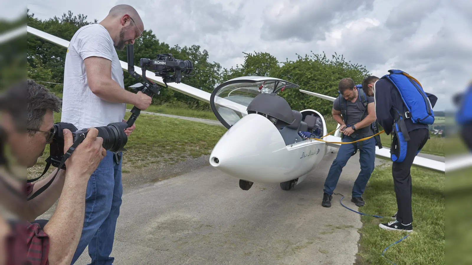 Über die Schulter geschaut: Paavo Blåfield (li.) und Kameramann Paul Maier (2.v.li.) bei Dreharbeiten für eine Filmszene bei den Hofgeismarer Segelfliegern. Mit dabei Segelflieger-Chef Christoph Danders (2.v.re.) und einer der Darsteller. (Foto: Stefan Bönning)